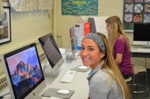 Two female Padua Franciscan High School students smiling as they work on Apple computers