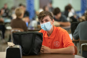 A male Padua Franciscan High School student sitting in the lunch cafeteria and wearing a mask during 2020