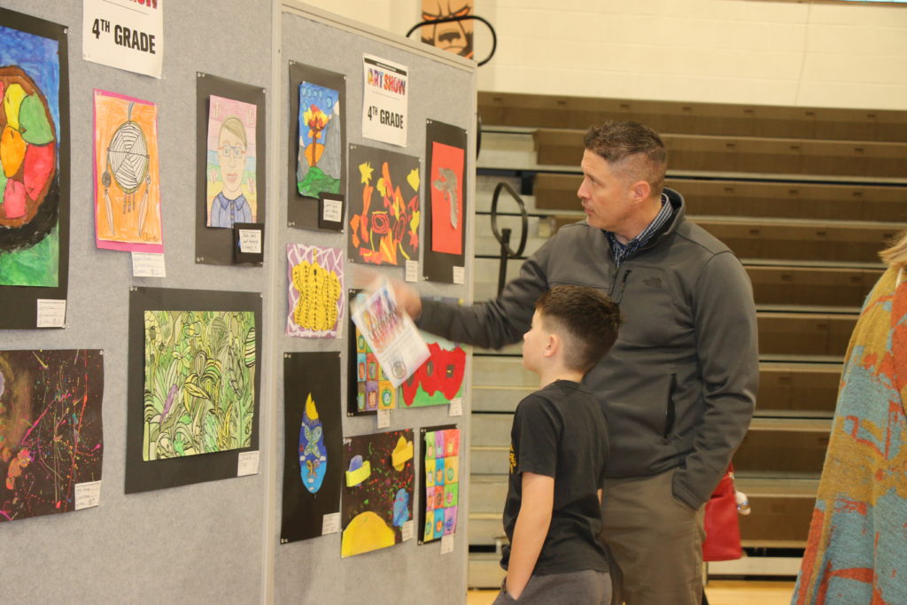 Father looking at artwork with his son at the Padua’s Elementary Art & Literary Show